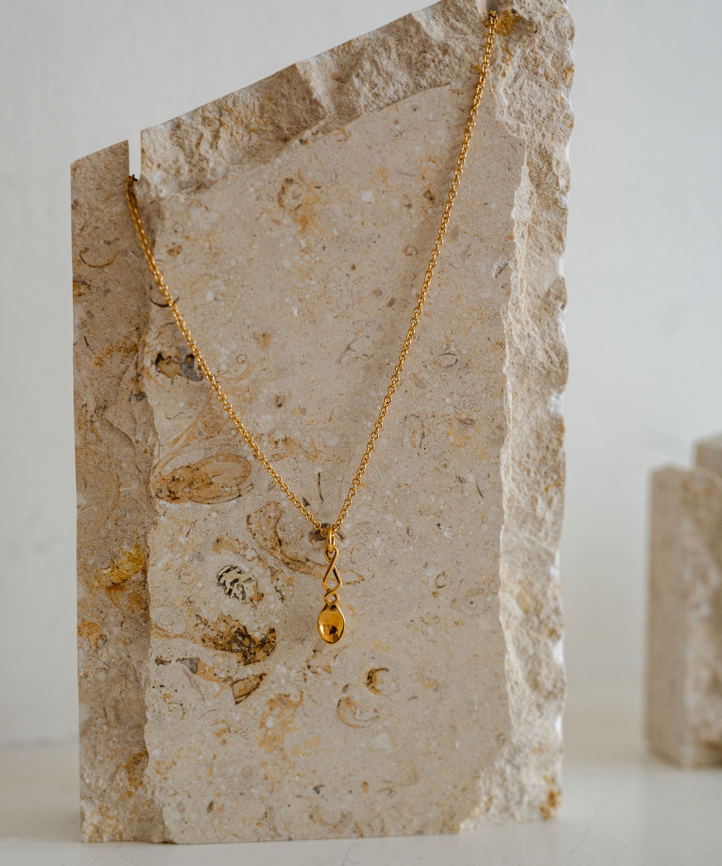 Lovespoon Gold necklace with a pendant on a stone surface