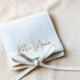 Beige pouch with 'Katie Marie' text tied with a ribbon on a beige background