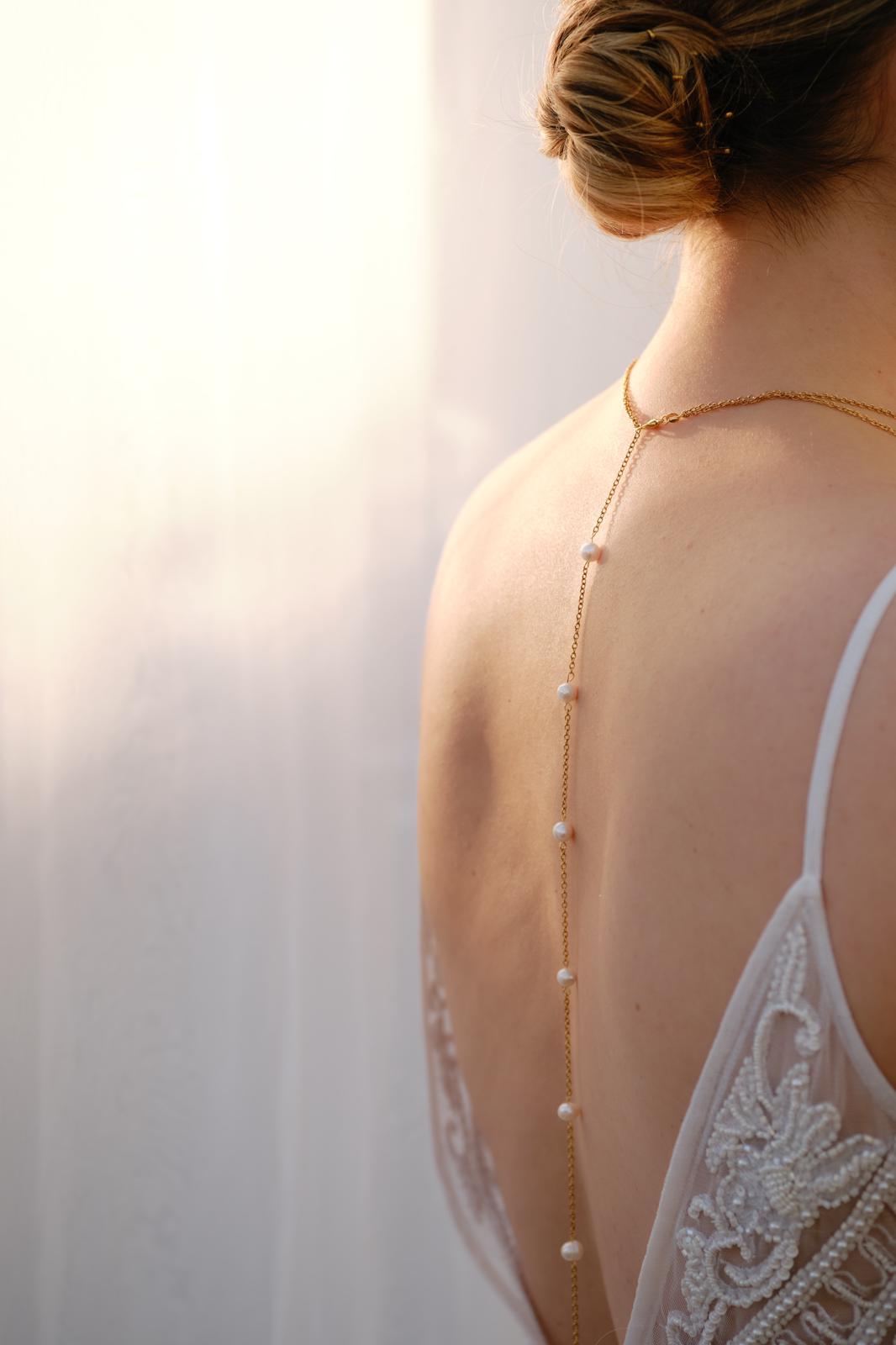 Bride wearing a handmade pearl back necklace with delicate gold chain and pearl accents, elegant wedding jewellery designed for open-back dresses.