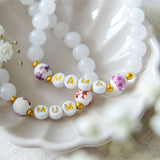 Handmade beaded bracelets spelling MUM and MAMA with white gemstone beads and floral accent beads, meaningful jewellery gifts for mums and Mother’s Day.