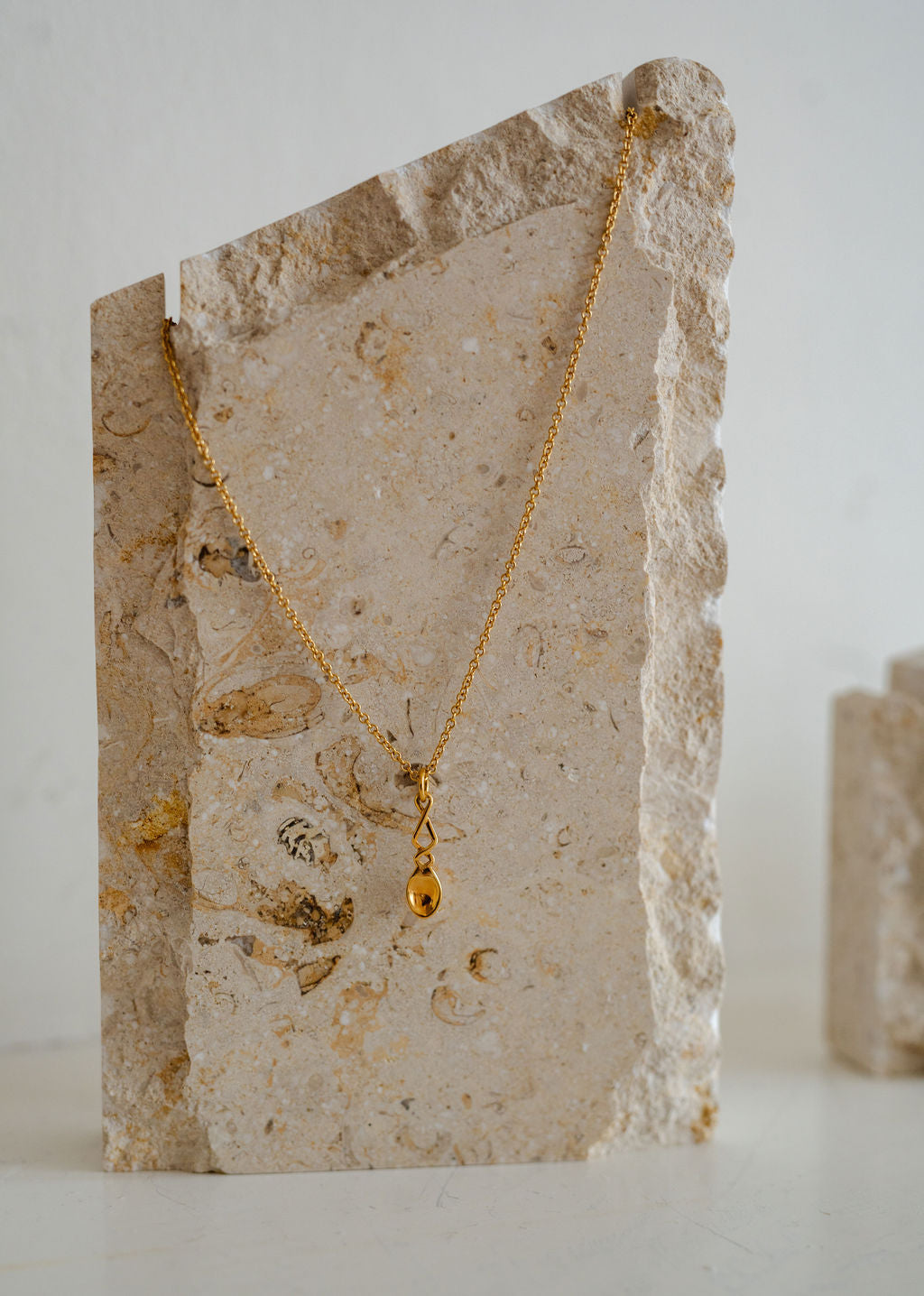 Lovespoon Gold necklace with a pendant on a stone surface