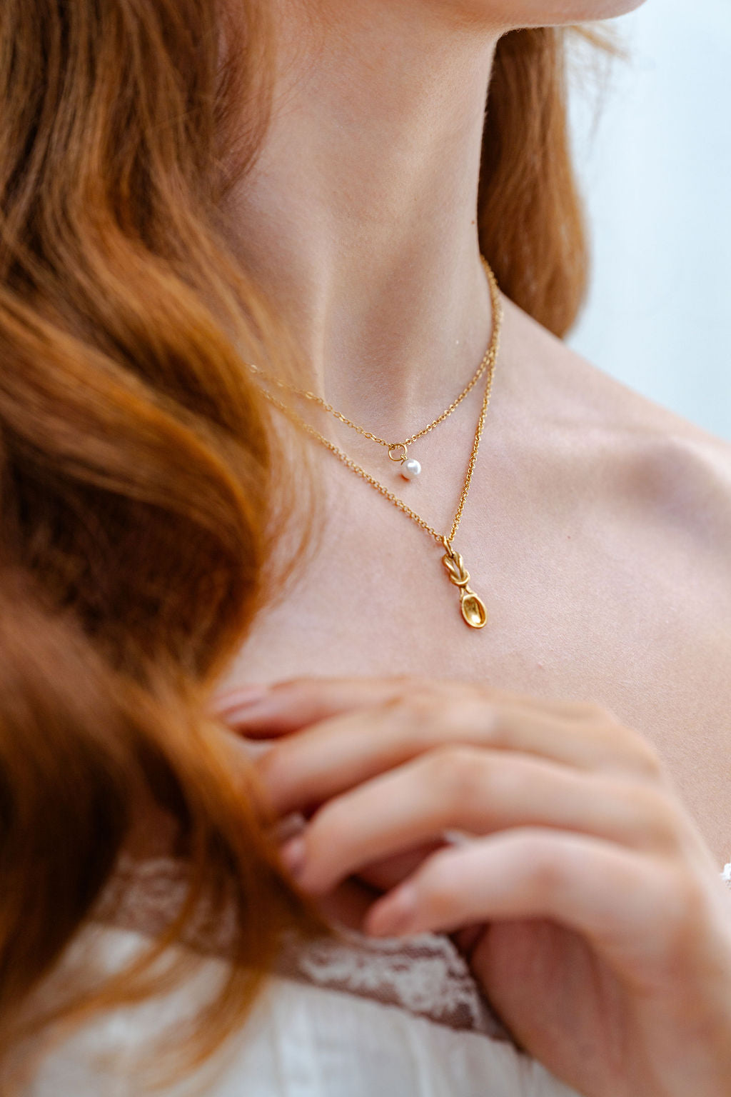 Close-up of a person wearing a gold necklace with a lovespoon pendant.