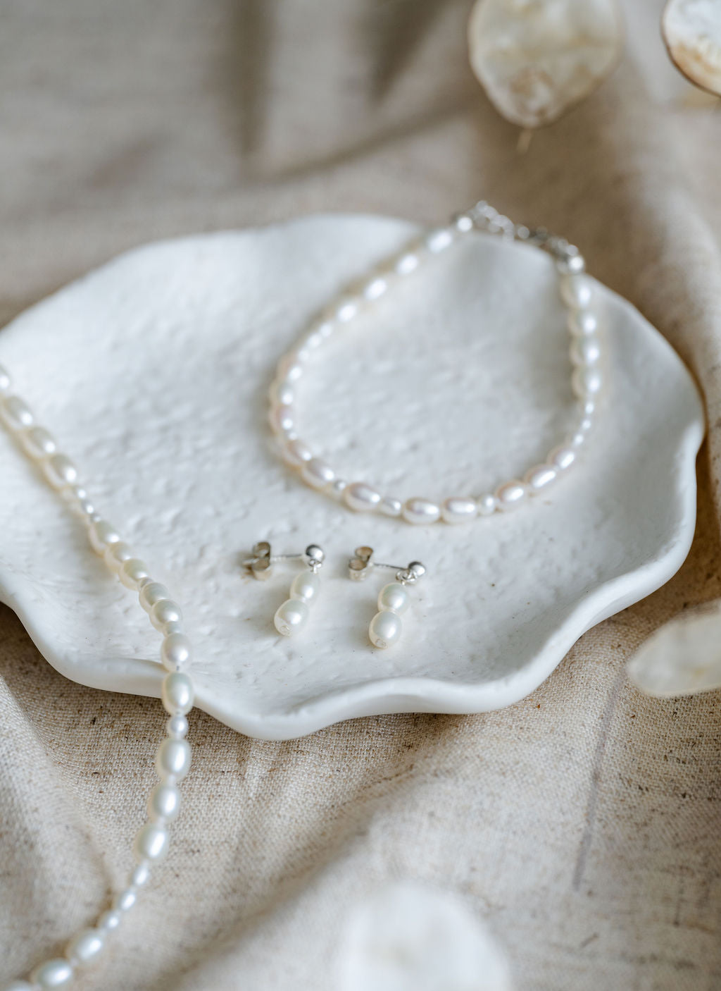Pearl necklace and earrings  and bracelet on a textured surface