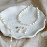 Pearl necklace and earrings  and bracelet on a textured surface