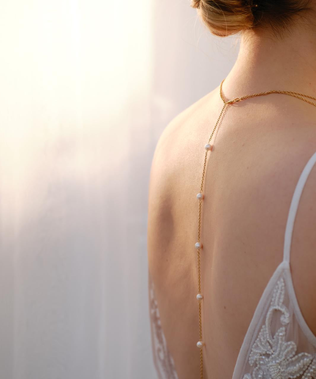 Bride wearing a handmade pearl back necklace with delicate gold chain and pearl accents, elegant wedding jewellery designed for open-back dresses.
