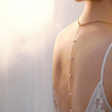 Bride wearing a handmade pearl back necklace with delicate gold chain and pearl accents, elegant wedding jewellery designed for open-back dresses.