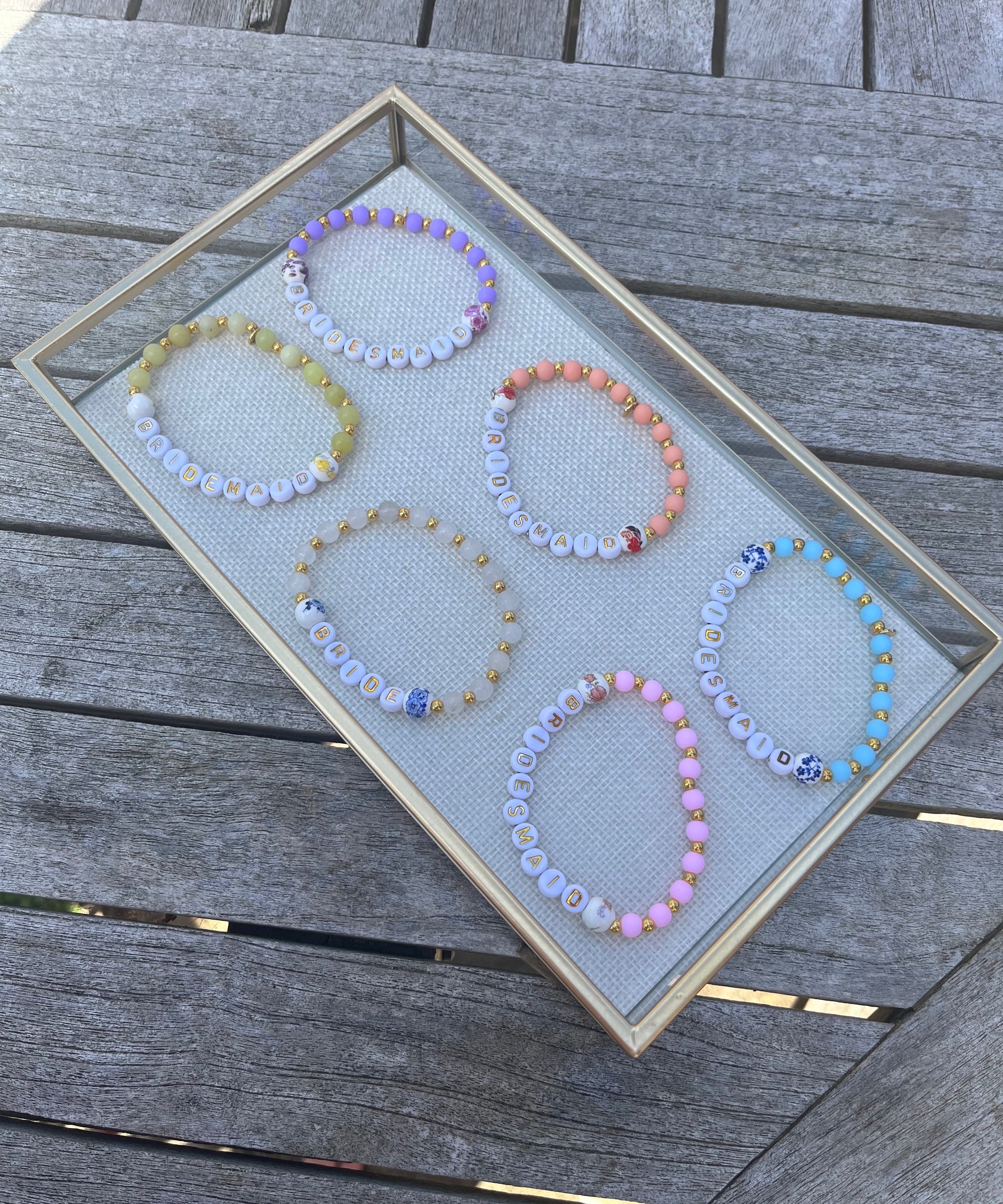 Collection of handmade beaded bracelets in pastel colours with BRIDE and BRIDESMAID letter beads, perfect personalised jewellery gifts for the bridal party.