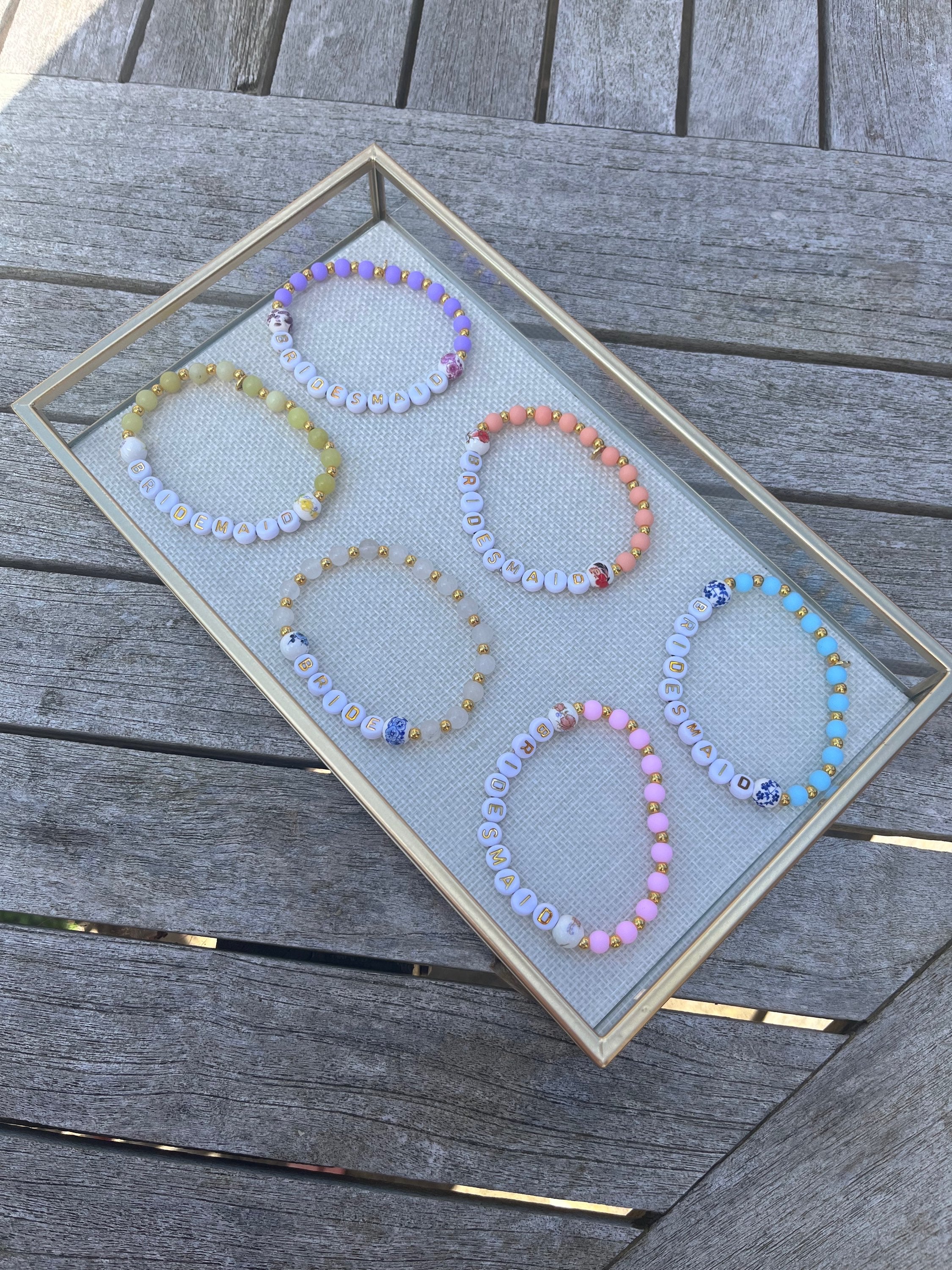Collection of handmade beaded bracelets in pastel colours with BRIDE and BRIDESMAID letter beads, perfect personalised jewellery gifts for the bridal party.