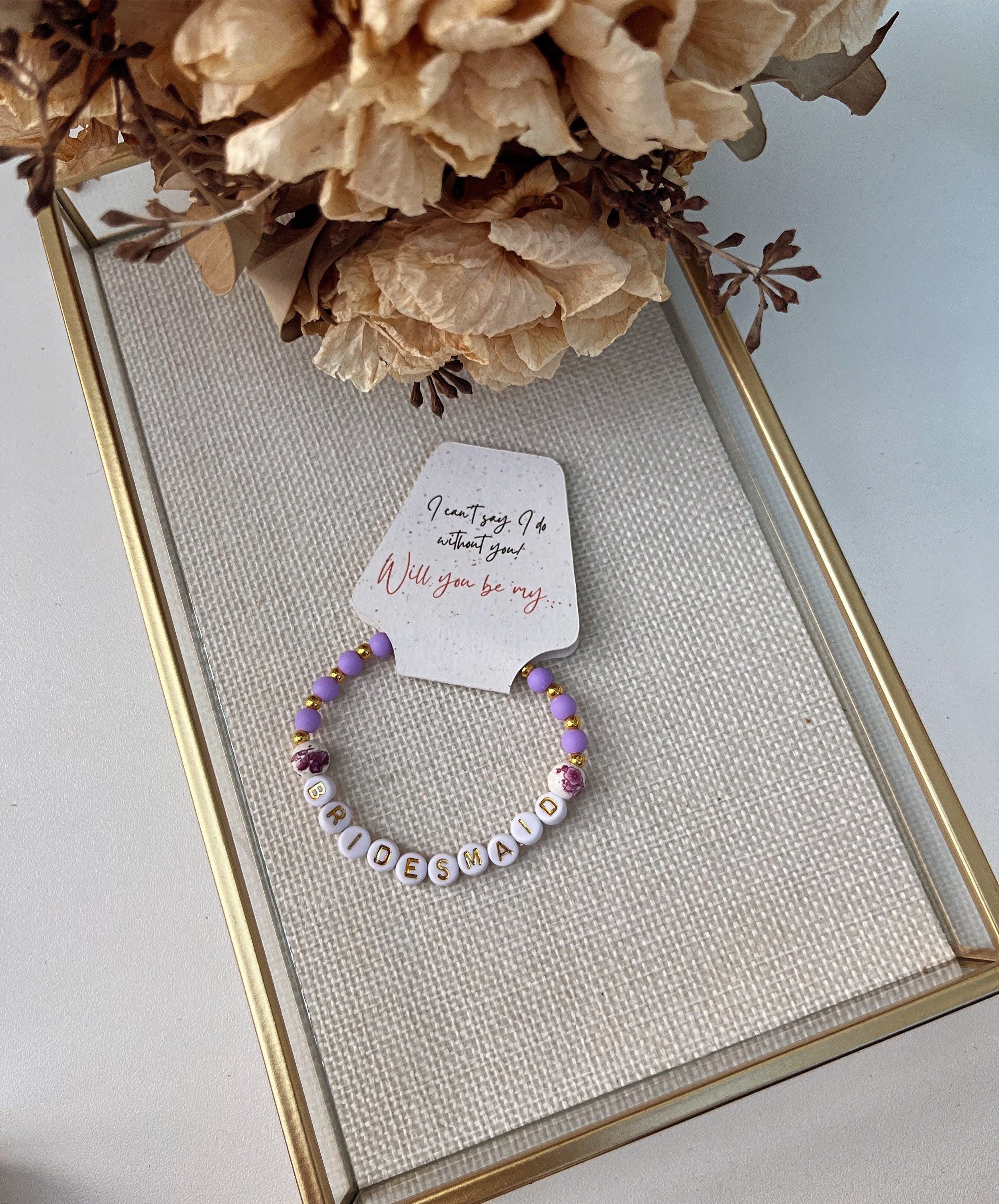 Purple beaded bridesmaid bracelet with gold accents and BRIDESMAID letter beads, displayed on a proposal card reading “Will you be my bridesmaid?”, a thoughtful wedding party gift.