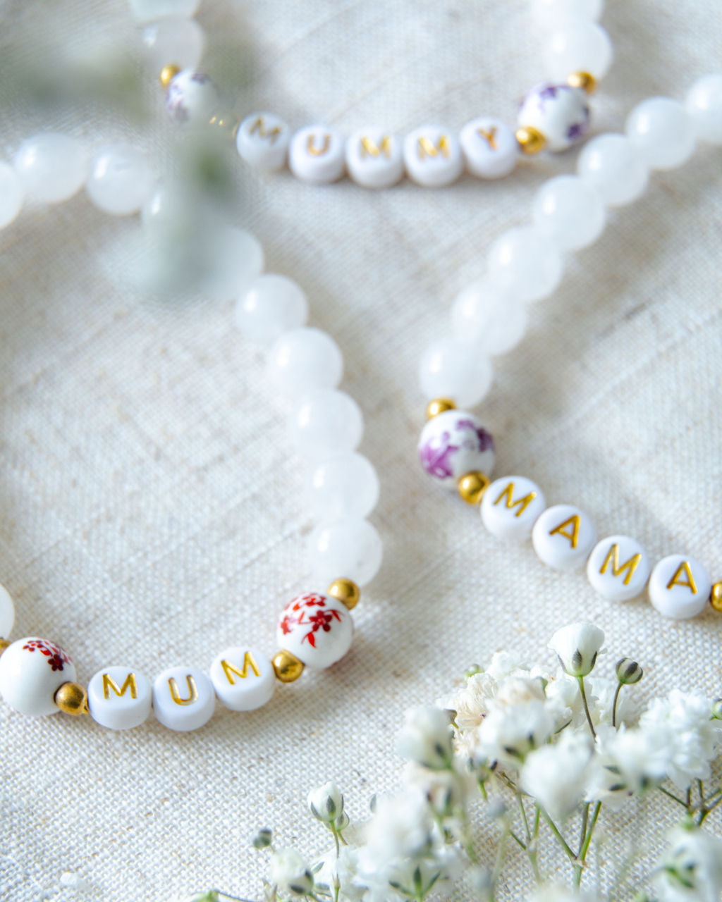 Handmade beaded bracelets spelling MUM, MAMA and MUMMY with white gemstone beads and gold accents, meaningful jewellery gifts for mums and new mothers.