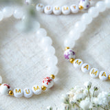 Handmade beaded bracelets spelling MUM, MAMA and MUMMY with white gemstone beads and gold accents, meaningful jewellery gifts for mums and new mothers.