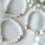 Set of handmade beaded bracelets spelling MUM, MUMMY and MAMA with white gemstone beads and gold lettering, thoughtful handmade jewellery gifts for mums.