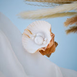 Elegant pearl bridal earrings displayed in a seashell with gold accents, handmade wedding jewellery for brides looking for timeless and romantic pearl accessories.