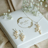 Pearl jewellery set with earrings and necklace on a branded box, surrounded by baby's breath flowers.